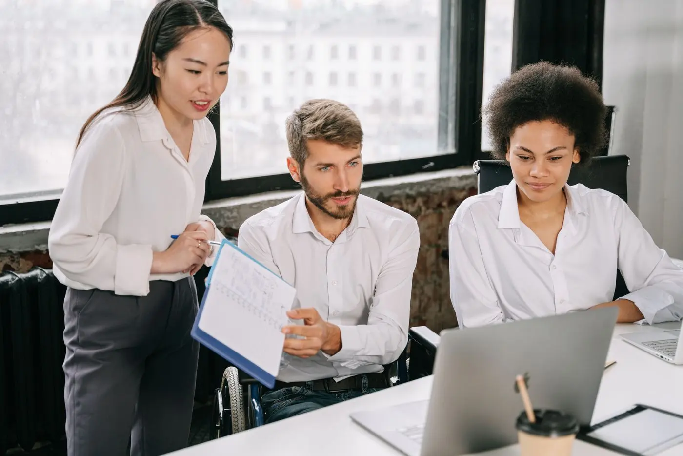 A diverse team working together on a laptop in a modern office setting, promoting inclusivity and collabora