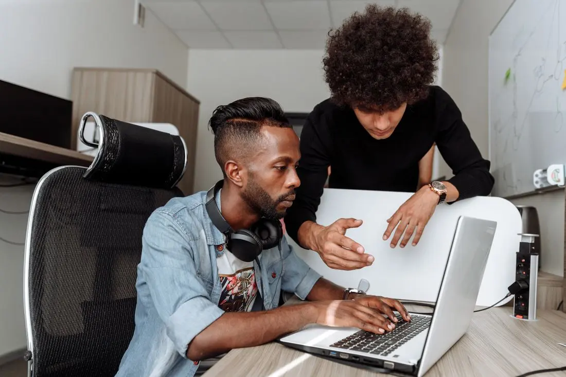 Two diverse male colleagues collaborating on a laptop in a modern office environment