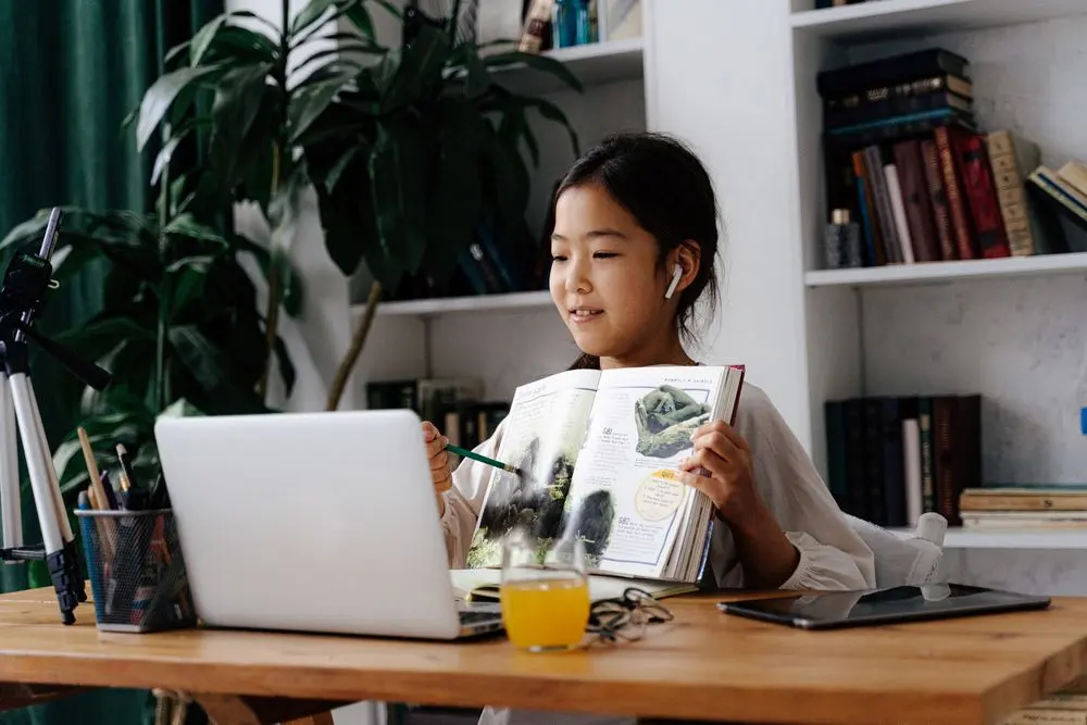 Child studying at home with a laptop and workbook