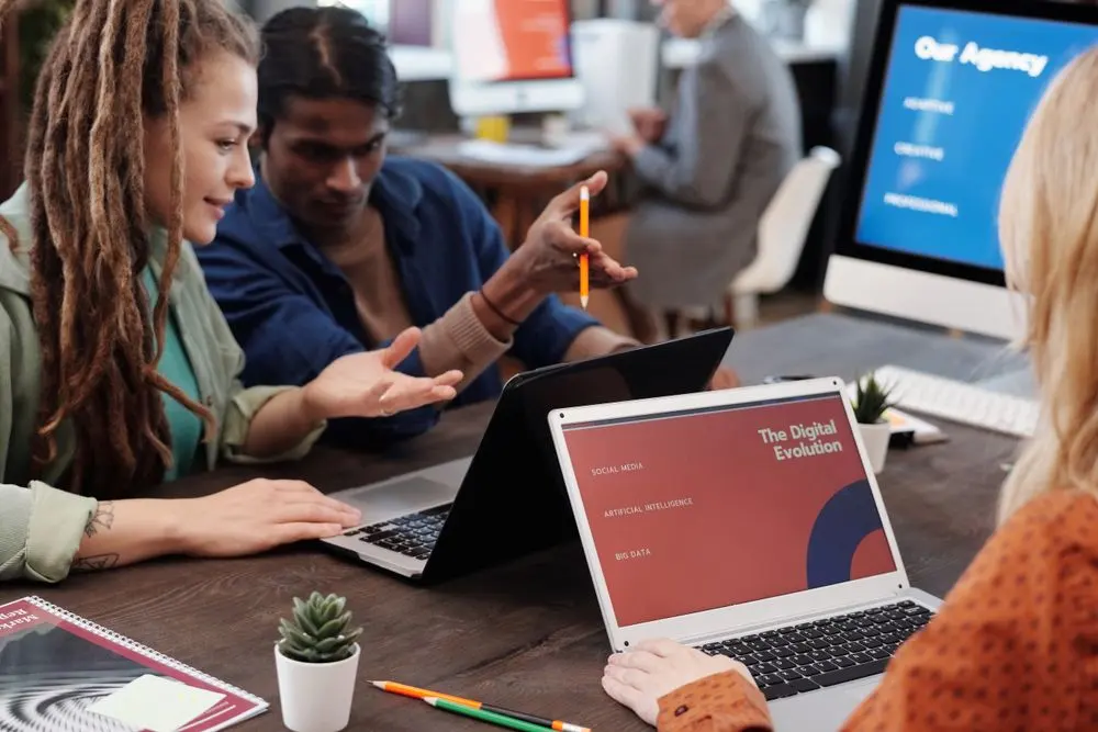 Marketing team reviewing work together around laptops