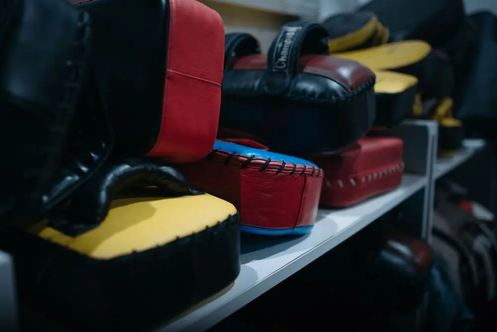 Training pads and gloves stacked on shelves in a gym