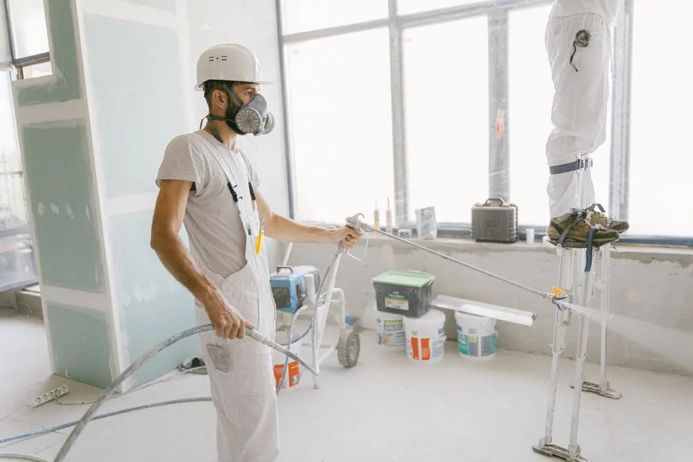 Painter using an airless spray gun on an interior wall