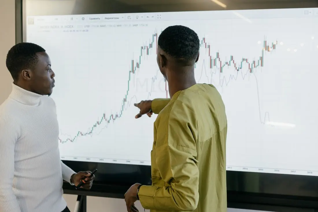Two professionals discussing financial trends on a graph at the office
