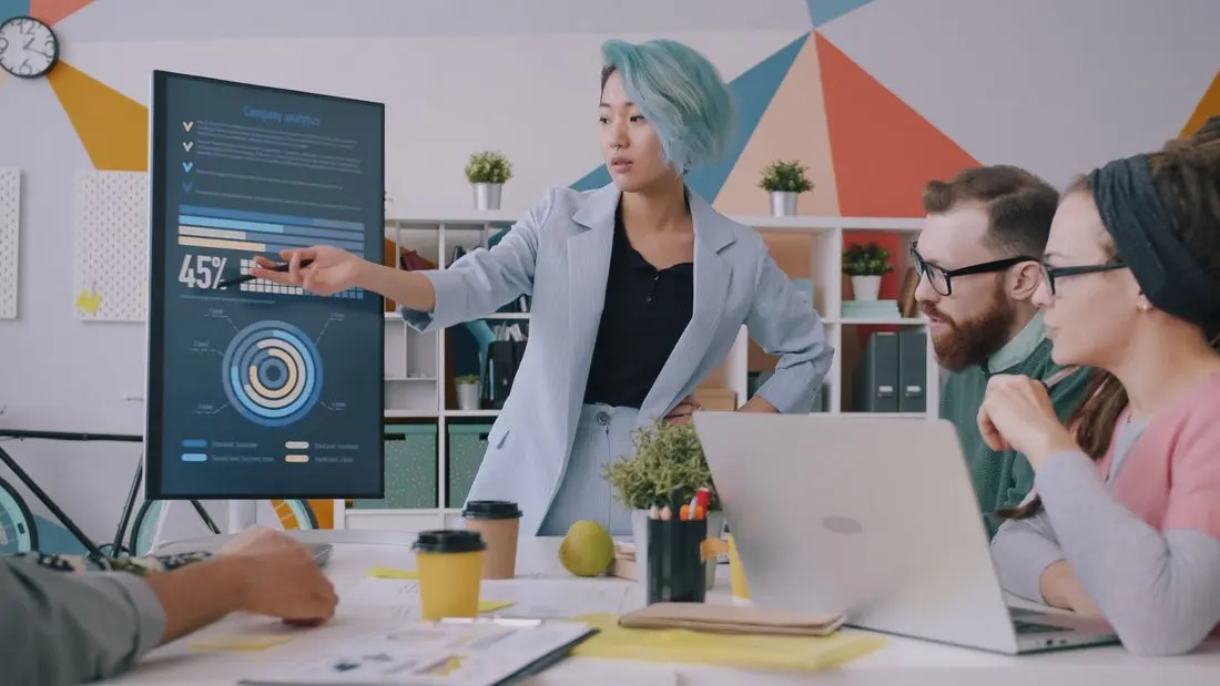 Diverse team meeting with data presentation on screen in modern office setting