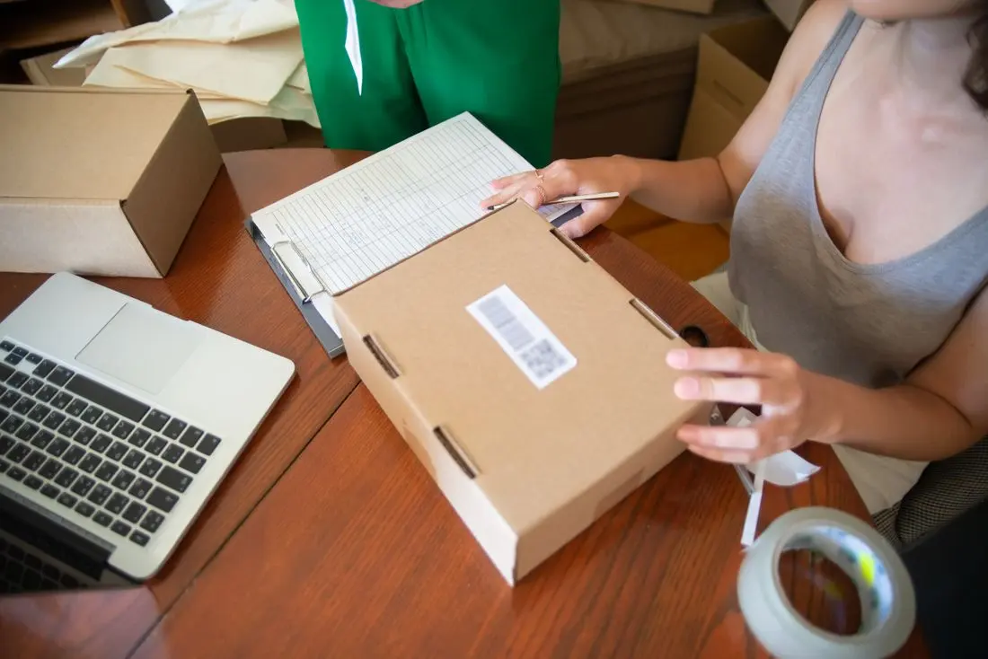 Two people packing online orders in a small business setting with a laptop